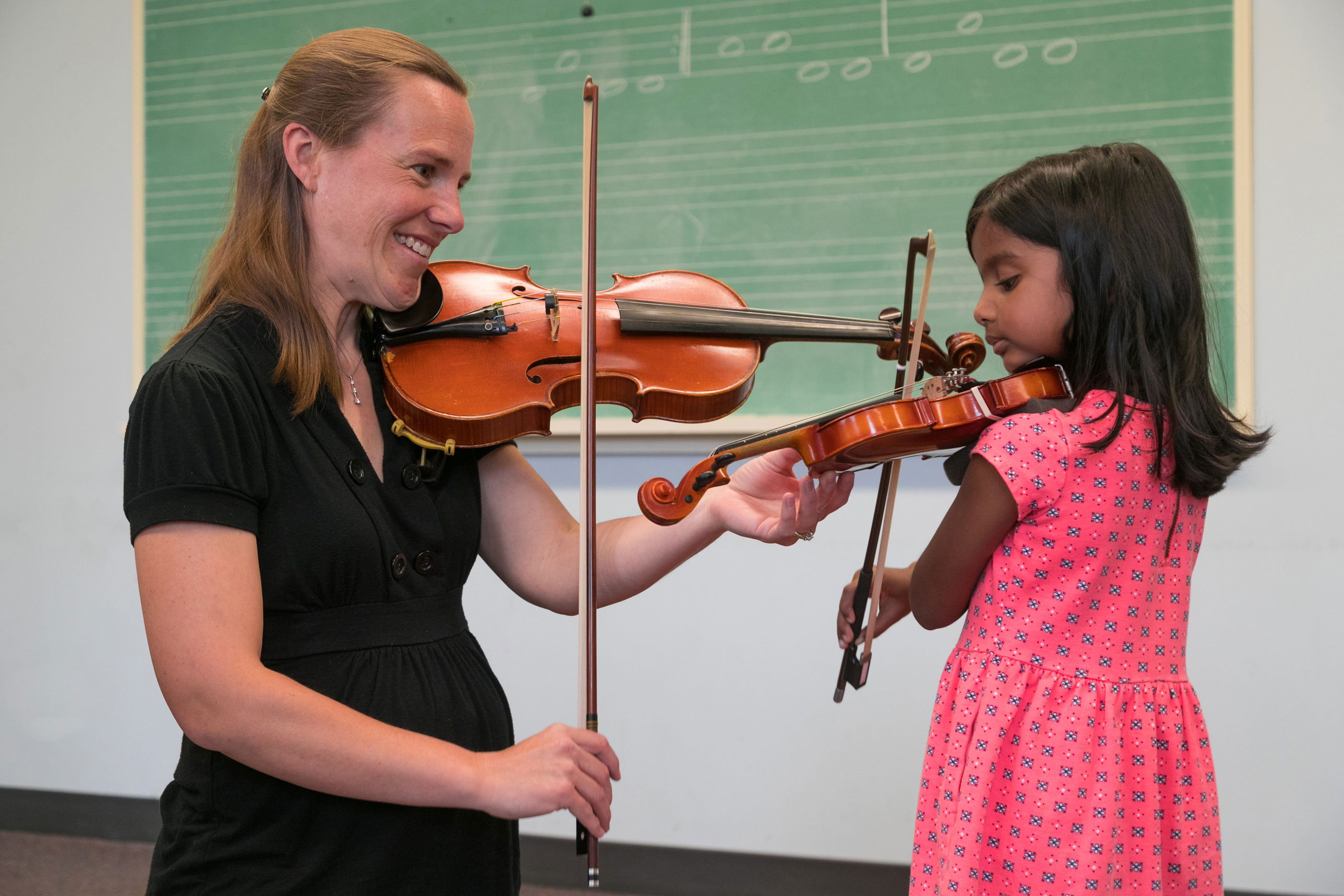 Young female child playing the violin with teacher