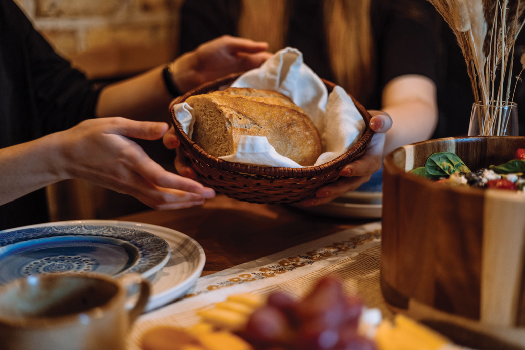 Passing basket of bread at a table