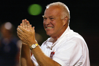 A smiling man wearing a white polo with the orange Wheaton 