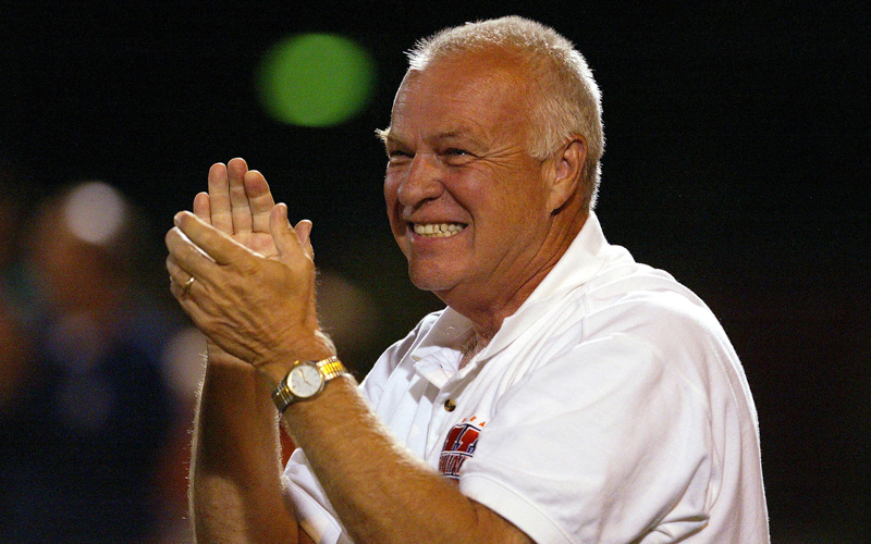 A smiling man wearing a white polo with the orange Wheaton 