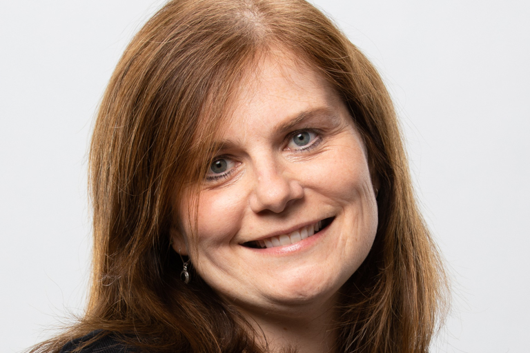 A ginger-haired woman wearing black smiles