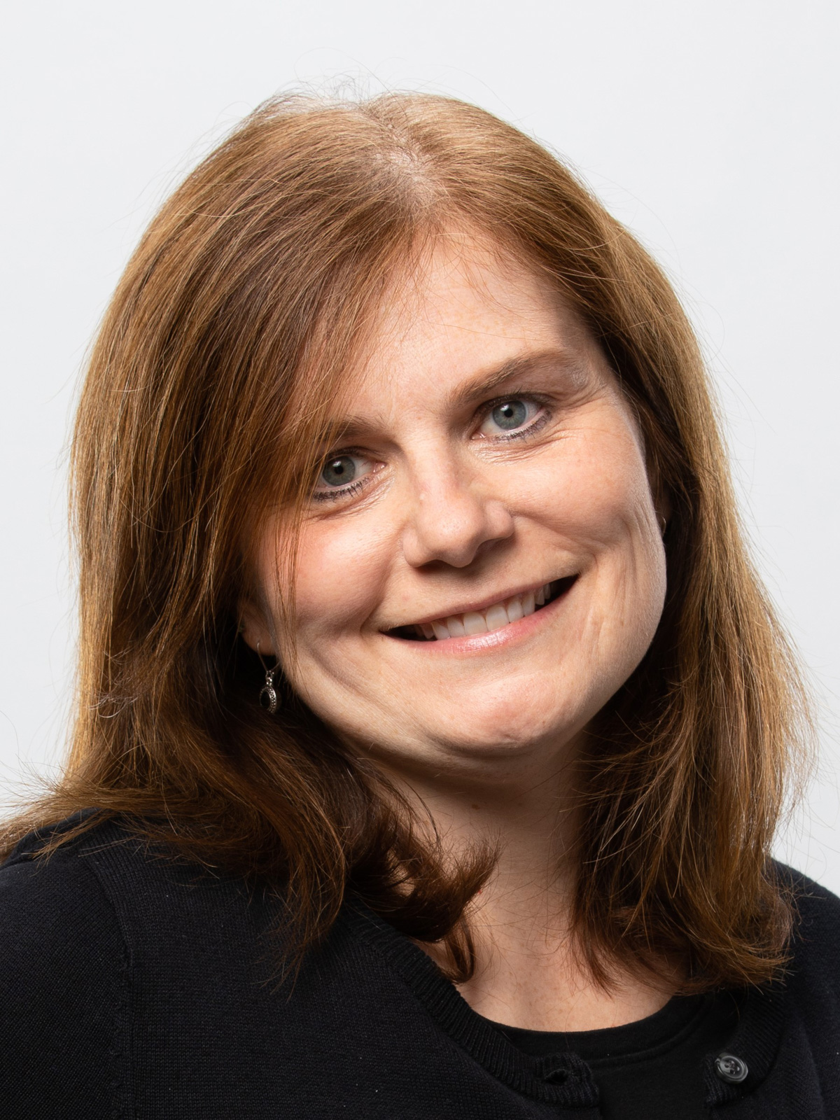 A ginger-haired woman wearing black smiles