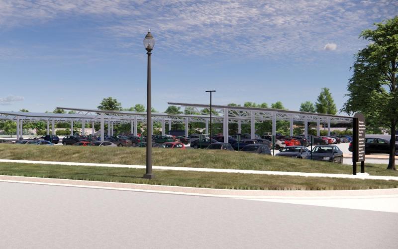 A filled parking lot that contains a structure of solar panels held up by thin columns